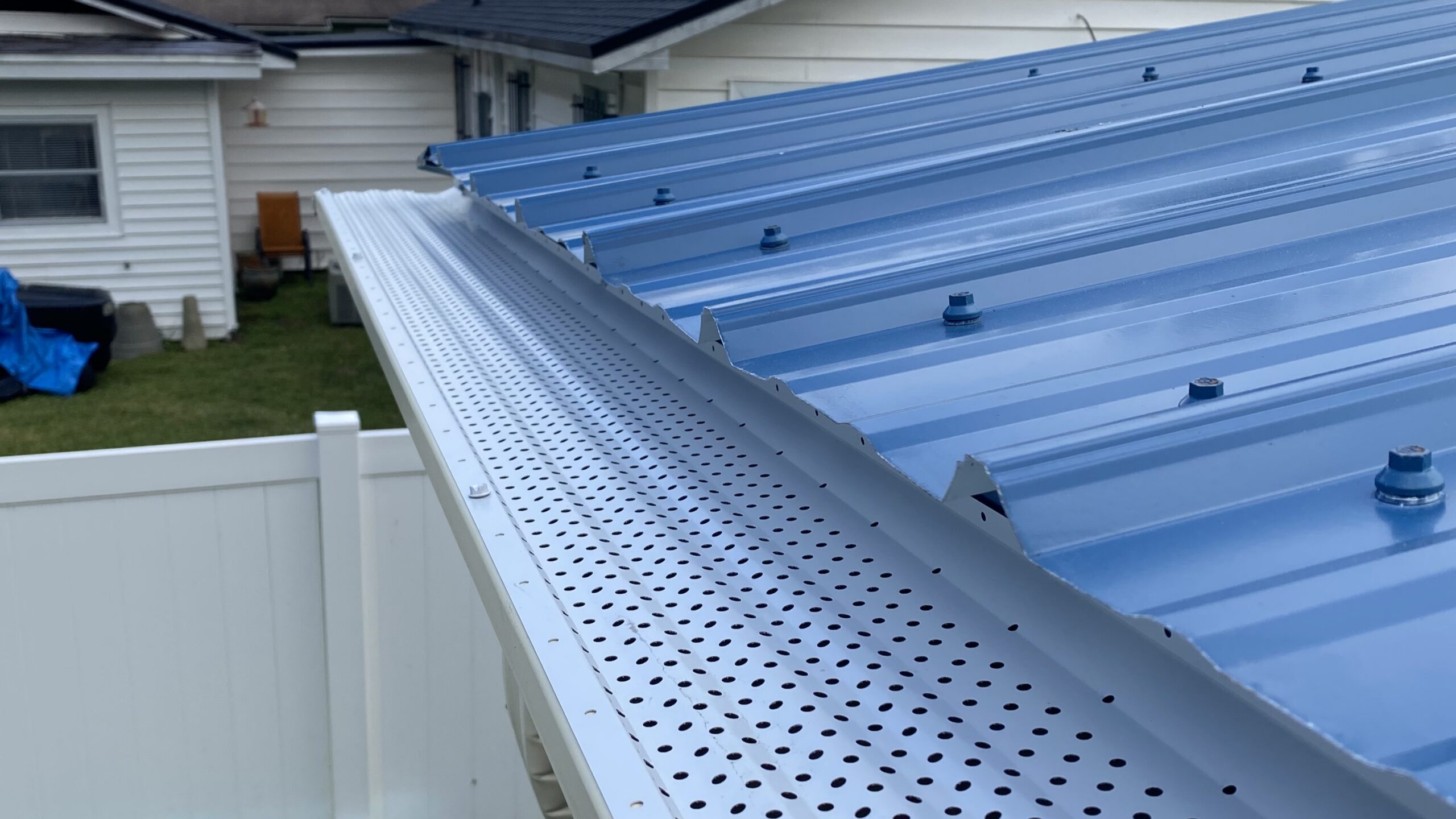 White leaf guard system installed along a blue metal roof in DeLand Florida