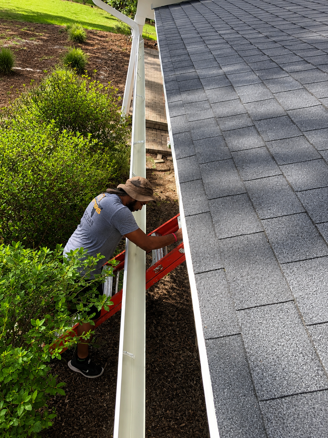 Worker going up the ladder to install gutter Installer climbing ladder to install seamless gutters on residential home in Oviedo, Florida